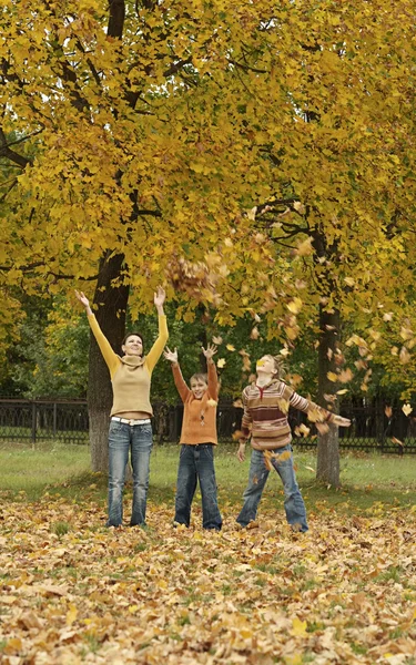 Mutter und ihre Kinder werfen Herbstblätter — Stockfoto