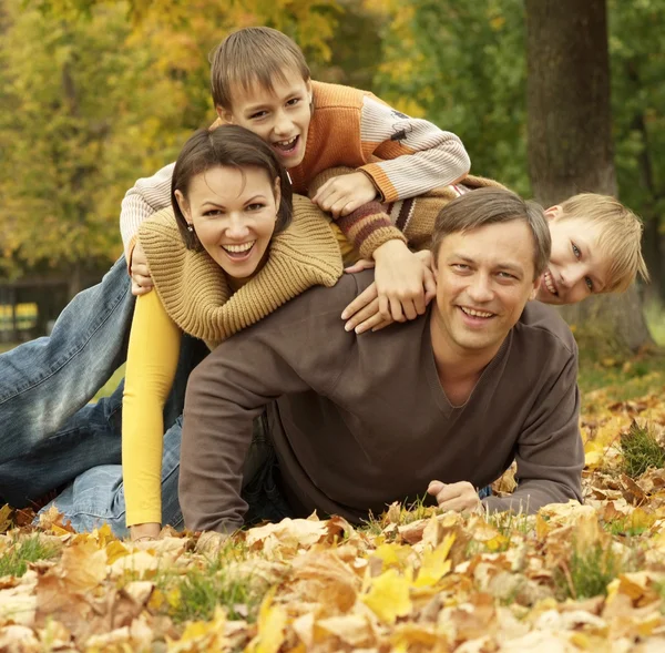 Šťastná rodina, ležící v podzimním parku — Stock fotografie