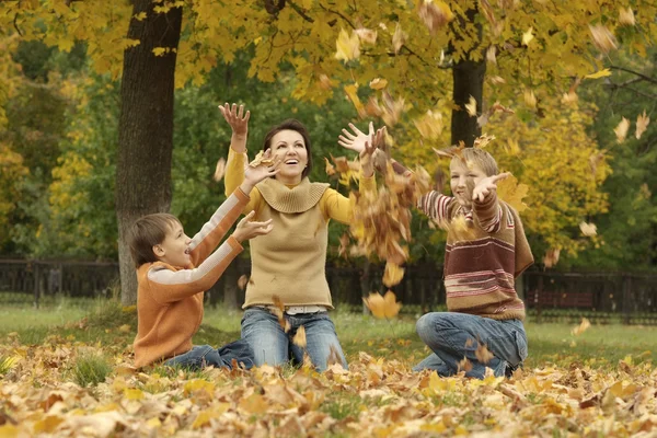 Mom and her children throwing autumn leaves — Stock Photo, Image