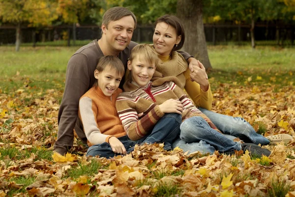 Family sitting in a autumn park — Stock Photo, Image