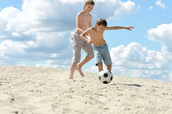 Två pojkar som spelar fotboll på en sand — Stockfoto