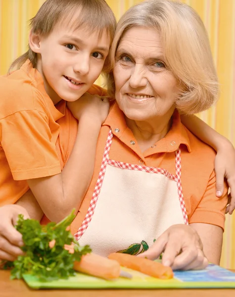 Glad äldre kvinna och pojken i orange i köket — Stockfoto