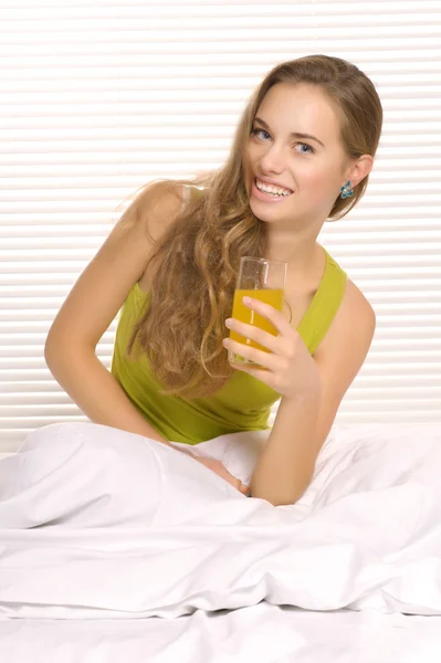 Chica beber jugo en la cama — Foto de Stock