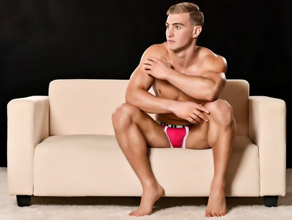 Seksowny mężczyzna siedzi na kanapie — Zdjęcie stockowe