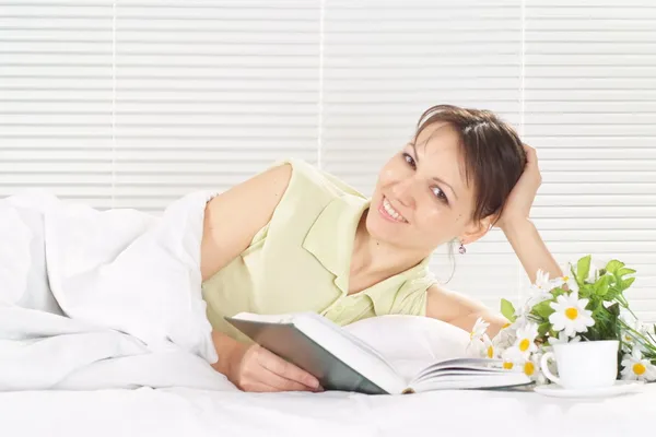 Woman lying in a bed of book — Stock Photo, Image