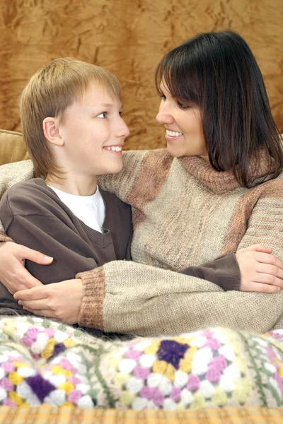 Schöne Mutter und Kind sitzen auf der Couch mit einer Tasse — Stockfoto