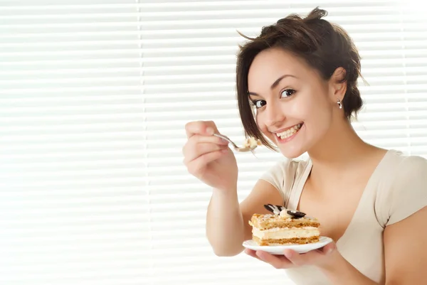 Yatakta bir pasta ile oturan genç beyaz kadın — Stok fotoğraf