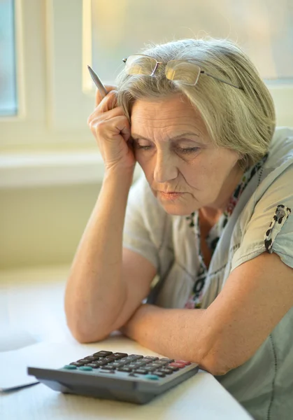 Mujer de edad avanzada grave con calculadora —  Fotos de Stock