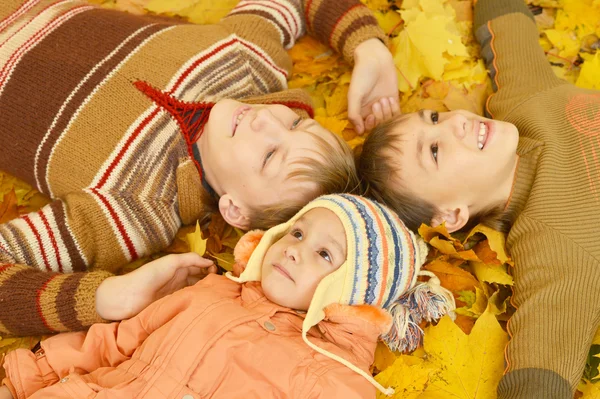 Familia de tres acostados sobre hojas amarillas —  Fotos de Stock