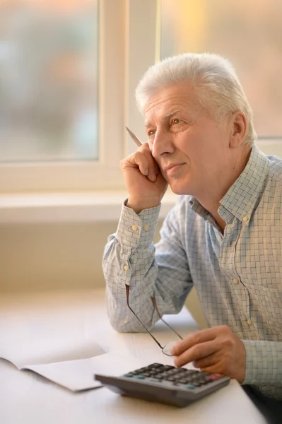 Serious elderly man with calculator — Stock Photo, Image