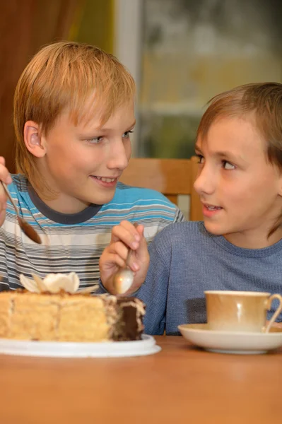 Dois irmãos pequenos comem bolo — Fotografia de Stock