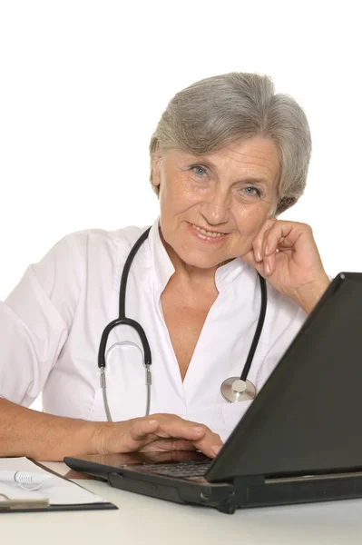 Elderly woman doctor sitting with laptop on white — Stock Photo, Image