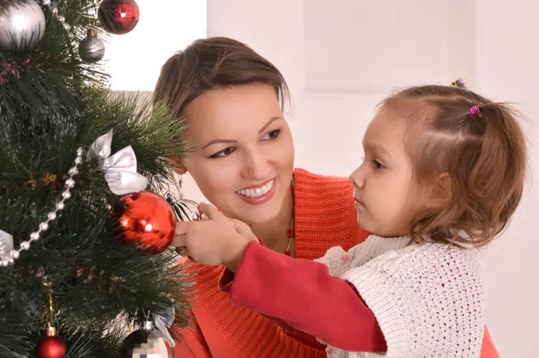 Прекрасная мать украшает рождественскую елку с дочерью — стоковое фото