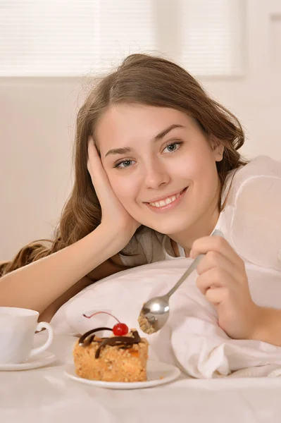 Unga kaukasiska kvinnan i sängen med tårta och saft — Stockfoto