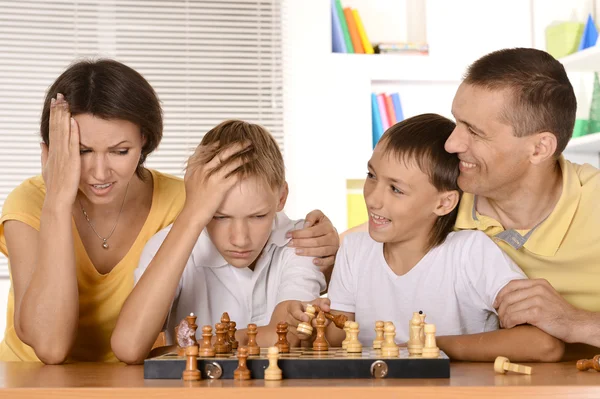 Familia feliz jugando ajedrez sentado en la mesa — Foto de Stock