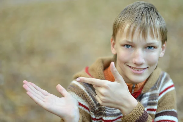 Smiling teenage boy pointing with his fingers on empty space — Stock Photo, Image