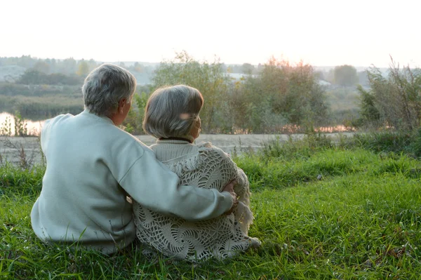 Elderly couple sitting in autumn nature — Stock Photo, Image
