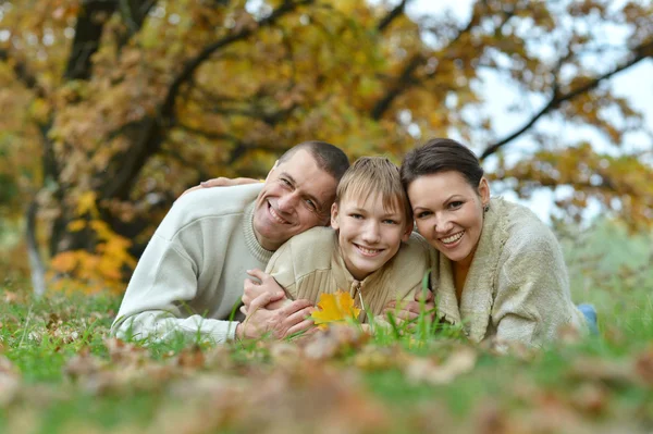 Família feliz no parque deitado em folhas amarelas — Fotografia de Stock