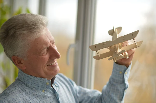 Пенсионер с деревянным самолетом дома — стоковое фото