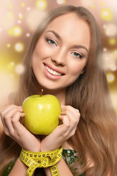 Vacker ung flicka med mätning av tejp och apple i händer — Stockfoto