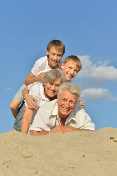 Família de quatro na areia — Fotografia de Stock