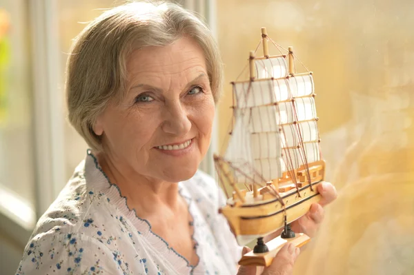 Старшая женщина с миниатюрным кораблем — стоковое фото