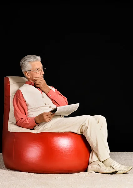 Зрелый мужчина, сидящий с газетой — стоковое фото