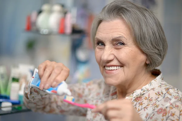 Mooie bejaarde vrouw haar tanden poetsen — Stockfoto