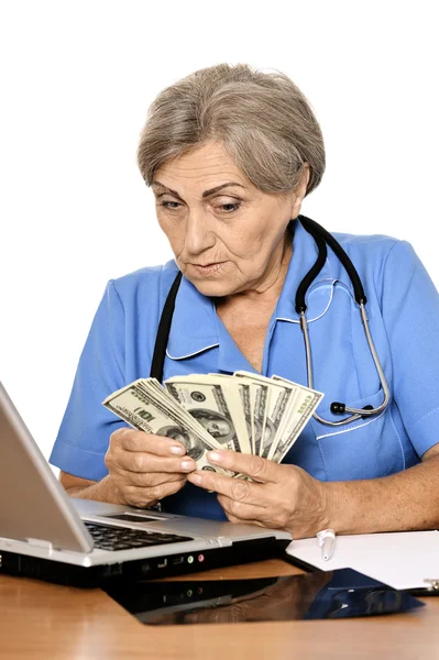 Старший врач с ноутбуком и долларами — стоковое фото