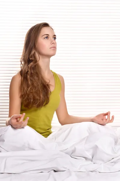 Красивая девушка медитирует в спальне — стоковое фото