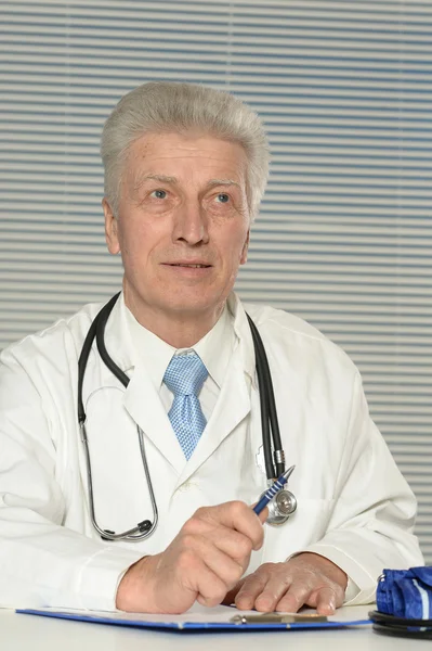 Пожилой врач за столом — стоковое фото
