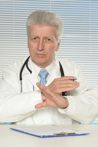 Elderly doctor at a table — Stock Photo, Image