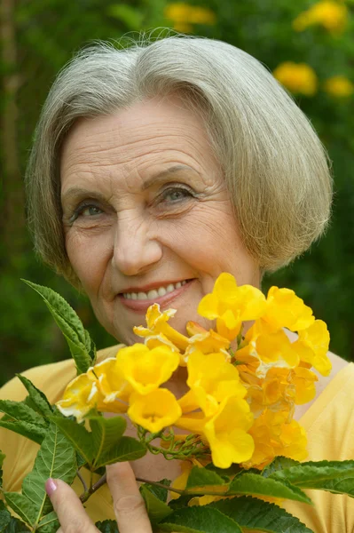 Senior vrouw met gele bloemen — Stockfoto