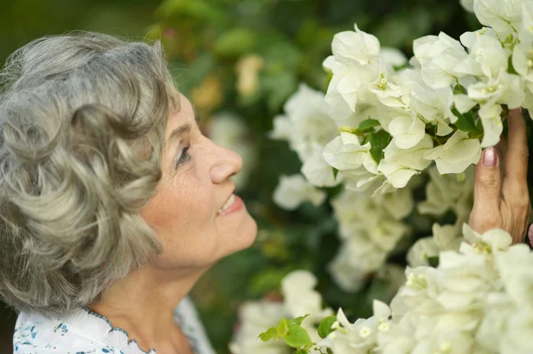 Äldre kvinna med vita blommor — Stockfoto