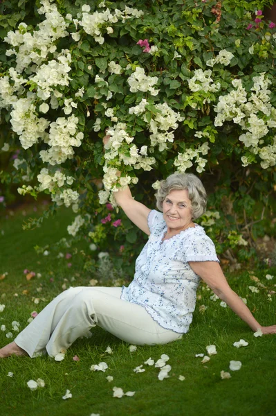 Ältere Frau mit weißen Blüten — Stockfoto