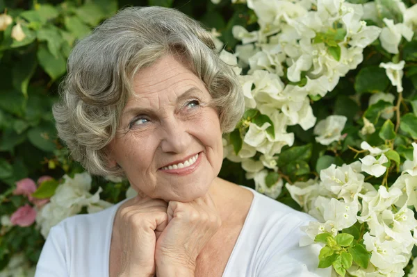 Oudere vrouw met witte bloemen — Stockfoto