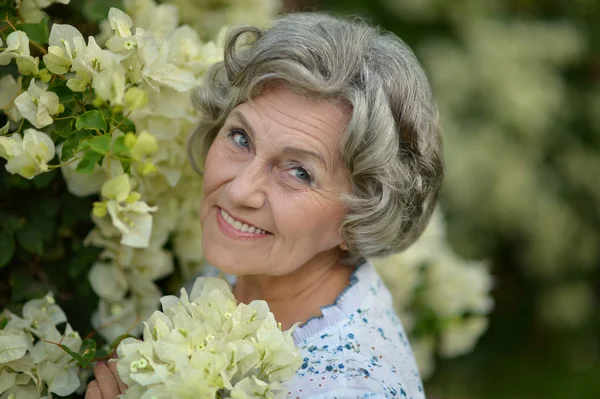 Oudere vrouw met witte bloemen — Stockfoto