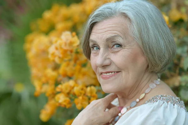 Mujer mayor con flores — Foto de Stock