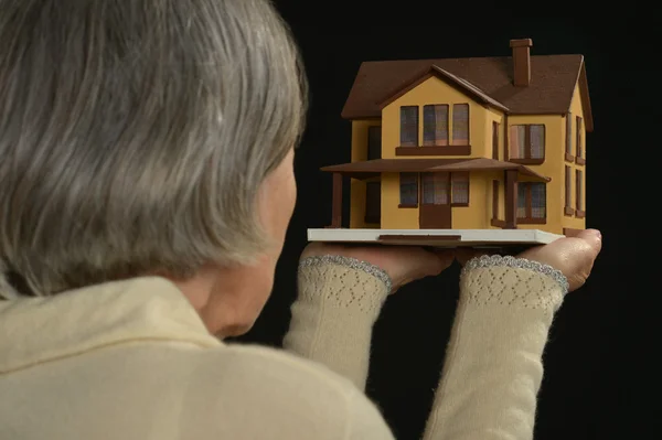 Старуха держит миниатюрный дом — стоковое фото