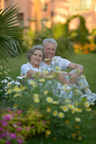 Starszy para siedzi w ogrodzie zwrotnik — Zdjęcie stockowe