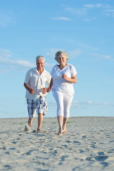 Old couple running on a beach — Stock Photo, Image