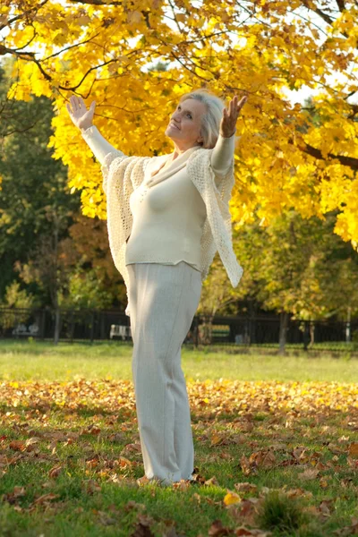 Donna anziana nel parco di autunno — Foto Stock