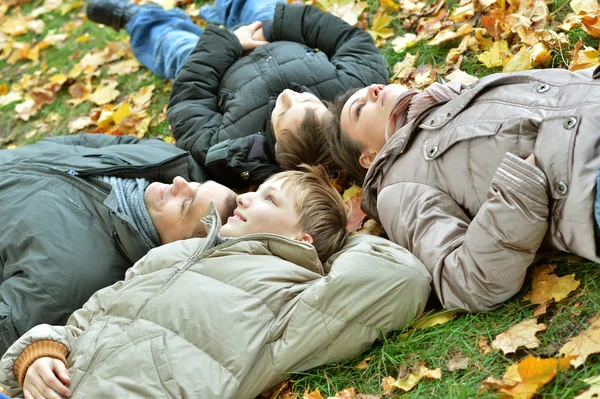 Счастливая семья лежит в осеннем парке — стоковое фото