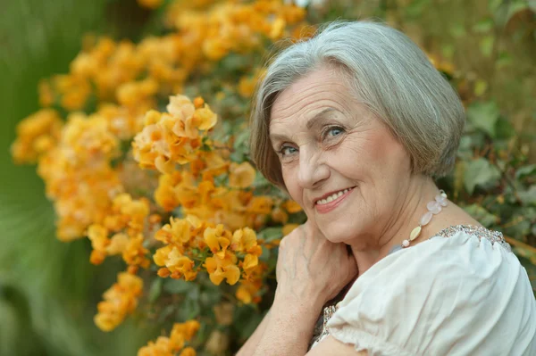 Senior vrouw met gele bloemen — Stockfoto