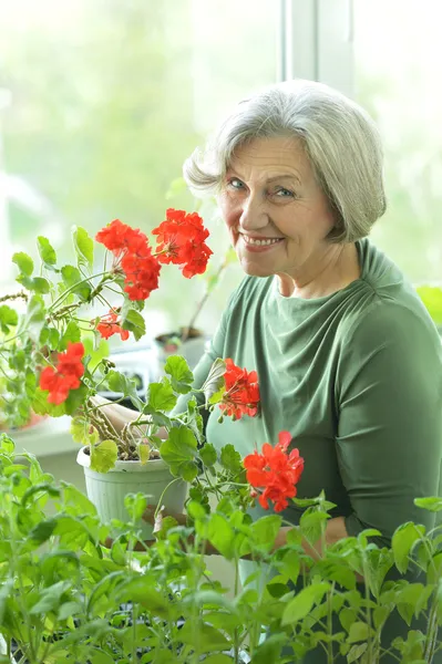 Seniorin mit roten Blumen — Stockfoto