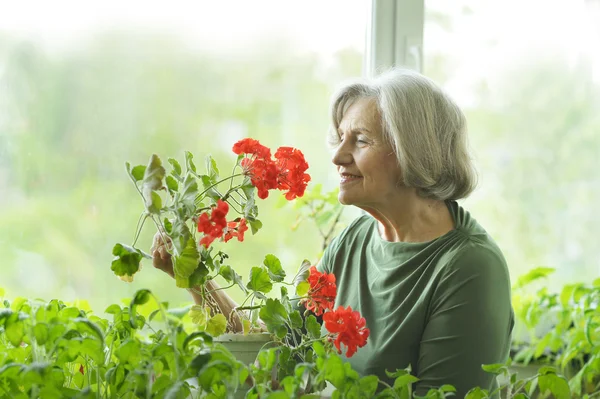 Starší žena s červenými květy — Stock fotografie