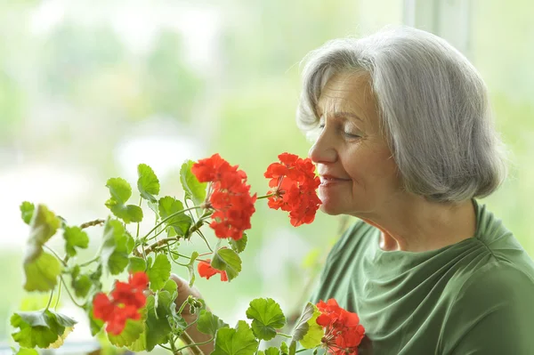Mulher sênior com flores vermelhas — Fotografia de Stock