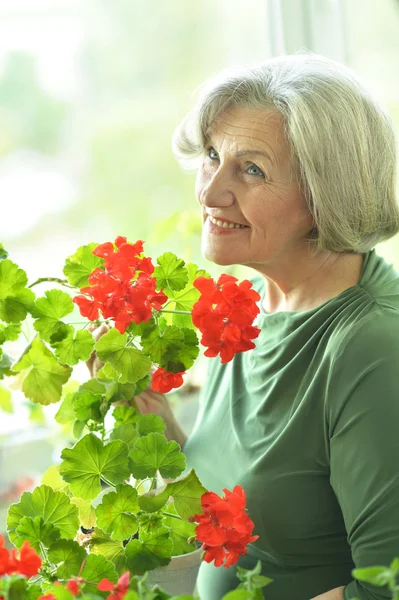 Seniorin mit roten Blumen — Stockfoto