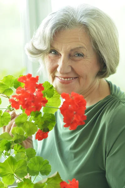 Femme âgée avec des fleurs rouges — Photo