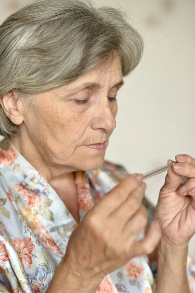 Vieille femme avec thermomètre — Photo